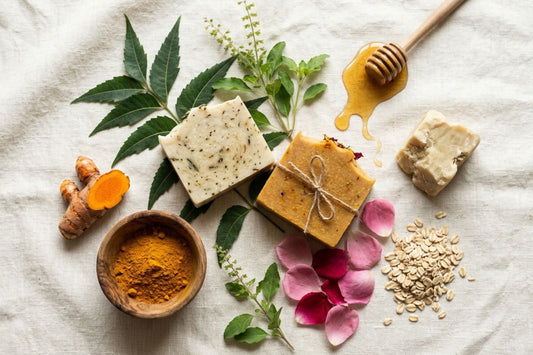 Flat-lay of natural ingredients used in Nivam soap — neem, tulsi, turmeric, rose, oats, honey and kokum butter