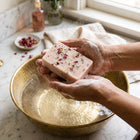 Nivam Kokum & Rose soap bar lathering in hands over a brass basin