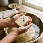 Nivam Oat & Honey soap bar lathering in hands over a brass basin